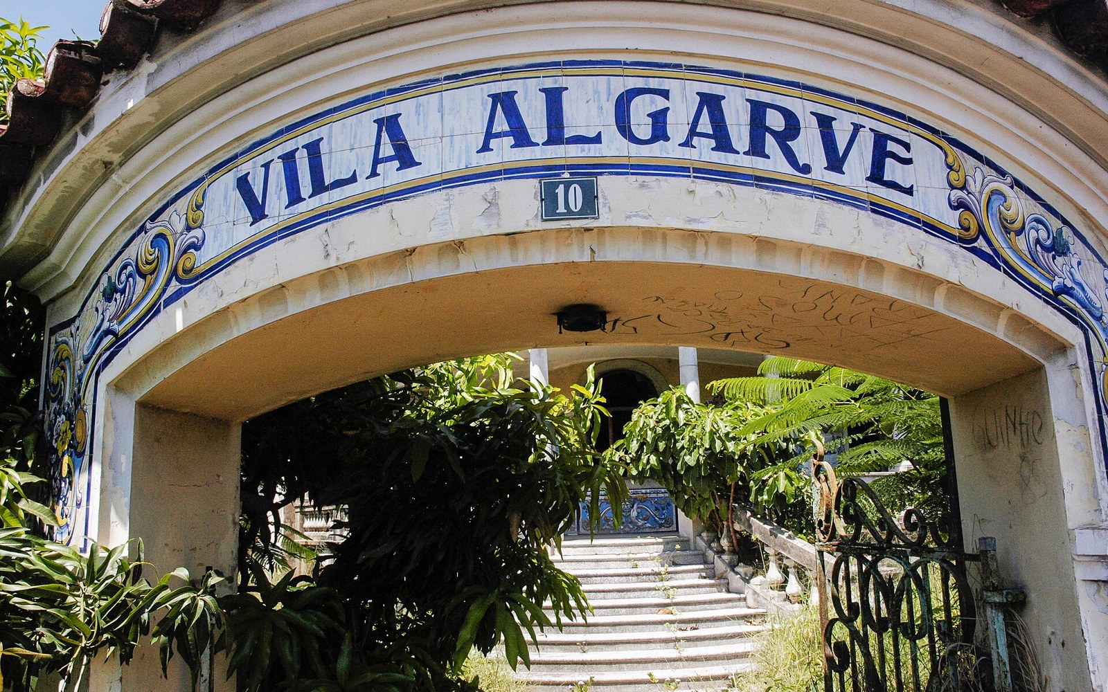 A tiled arched entrance in Maputo with steps climbing into an overgrown garden